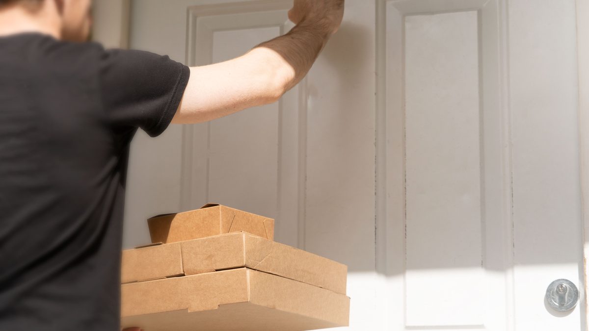 A delivery driver knocking on a door with packages