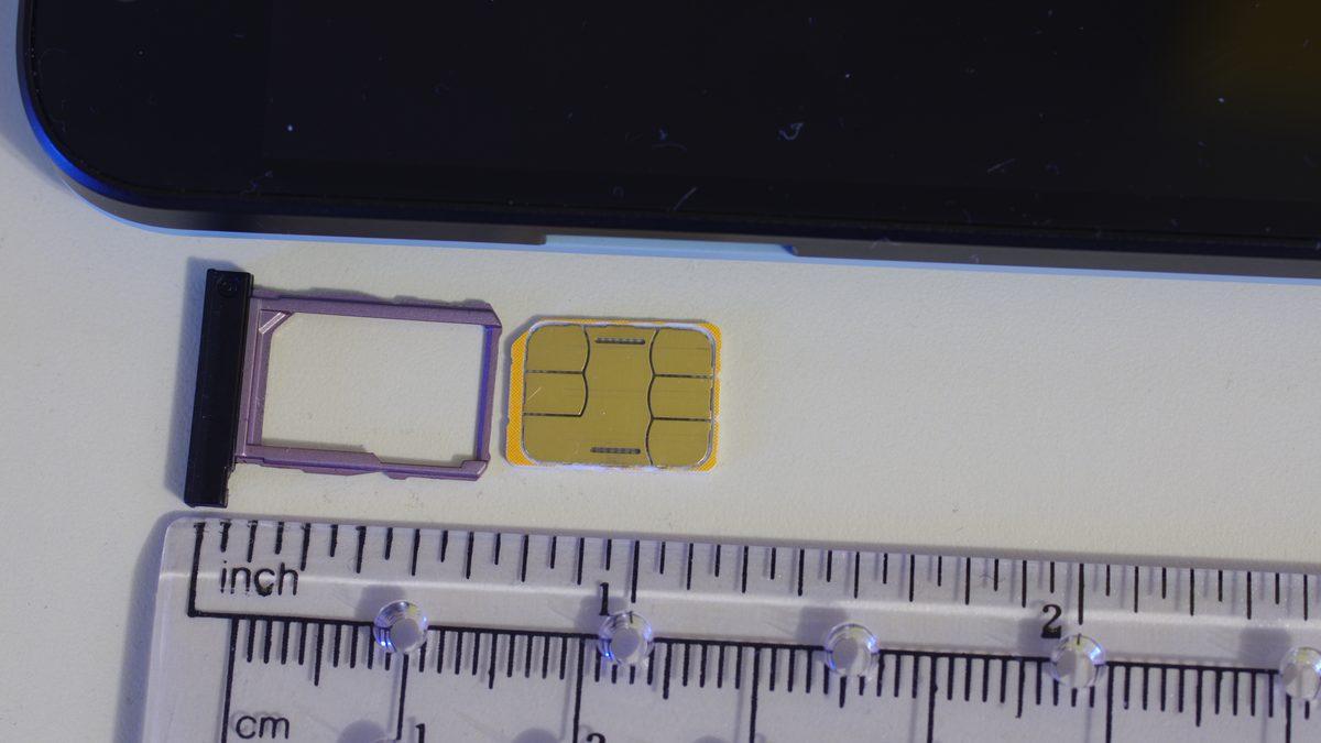 A SIM card and tray next to a ruler